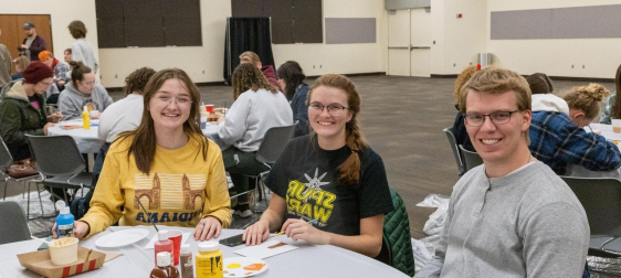 An image of some SUU students sitting at a table smiling.